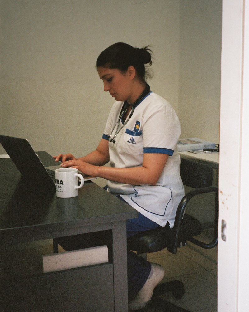 Veterinaria mexicana en sus 40 revisa su laptop en la trastienda de su pequeña clínica