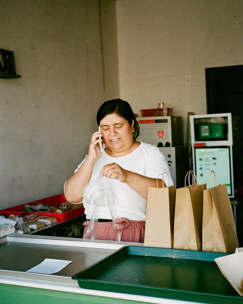 Dueña de una panadería revisa un mensaje en su celular detrás del mostrador